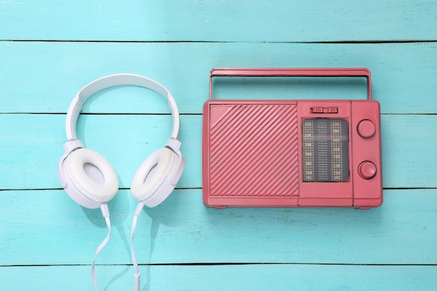 Auriculares blancos con receptor de radio sobre fondo de madera azul diseño de música creativa vista superior endecha plana