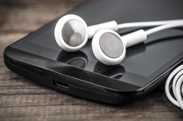 Auriculares blancos en smartphone negro