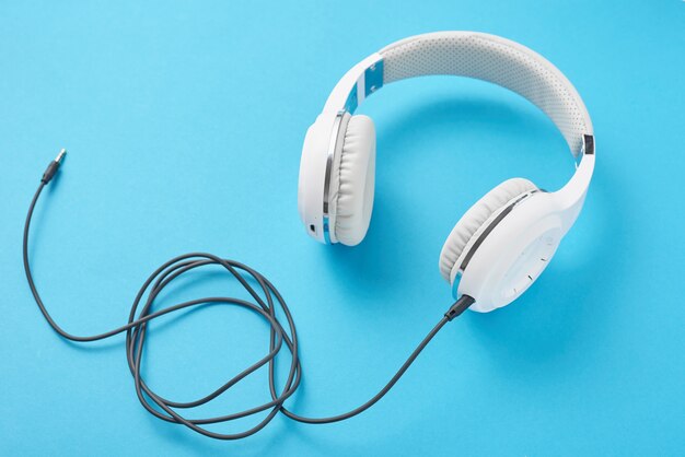 Auriculares blancos sobre azul pastel.