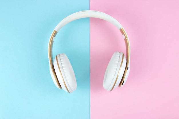 Auriculares blancos sobre fondo azul pastel rosa.