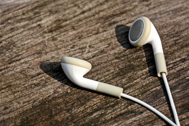 Auriculares blancos sobre fondo de madera vieja