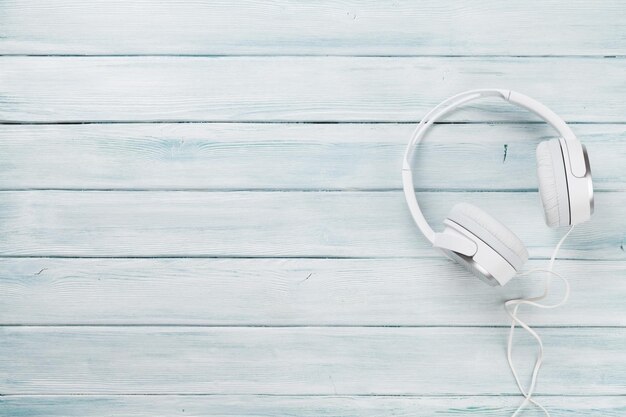 Auriculares blancos para sonido musical en mesa de madera.