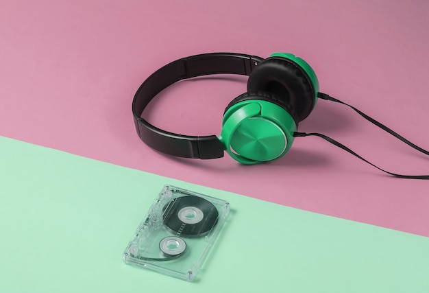 Auriculares con cable con casete de audio sobre fondo pastel rosa verde. Estilo retro, DJ. Concepto de música minimalista.