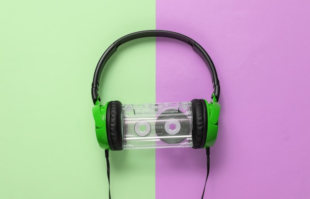 Foto auriculares con cable con casete de audio sobre fondo pastel rosa verde. estilo retro, dj. vista superior, concepto de música minimalista.