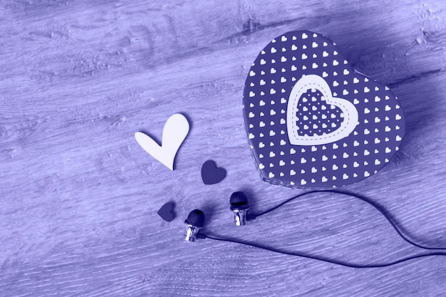 Foto auriculares y una caja de regalo en forma de corazón y pequeños corazones sobre un fondo muy peri concepto de regalo musical vista superior con espacio de copia