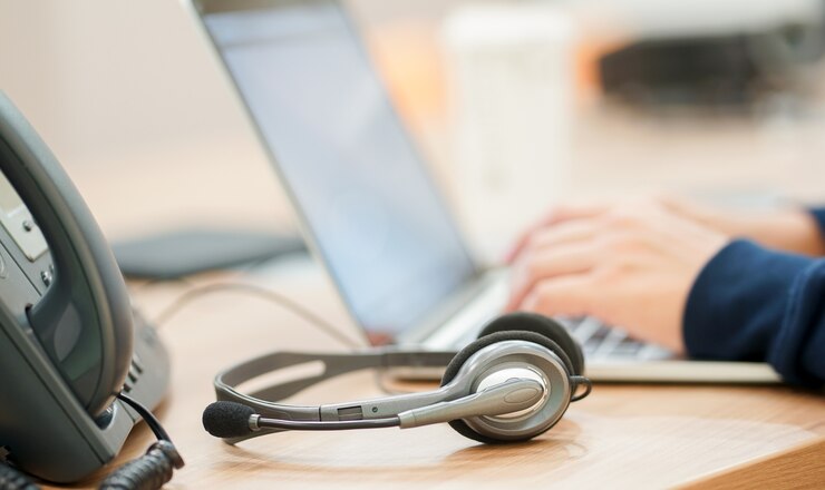 Foto auriculares de cerca con el tipo de mano de hombre trabajo en el teclado portátil con el escritorio de la oficina telefónica