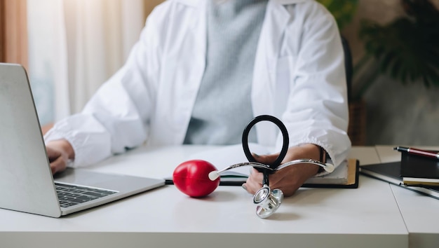 Auriculares con corazones rojos en las manos de los médicos e información del paciente en la mesaDiagnóstico médico e historial de pacientesxA