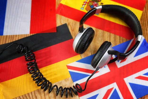 Auriculares del curso de idiomas y bandera en la mesa de madera