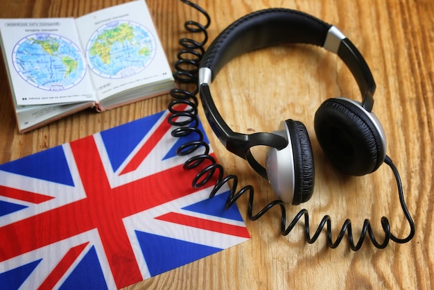 Auriculares del curso de idiomas y bandera en la mesa de madera