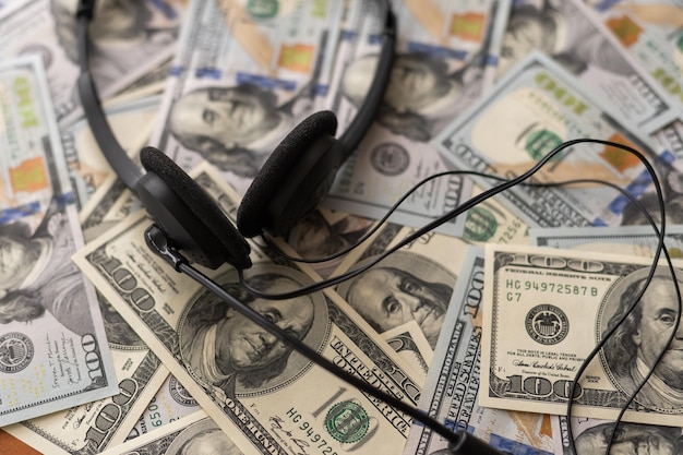 Auriculares y dinero en efectivo estadounidense en la mesa