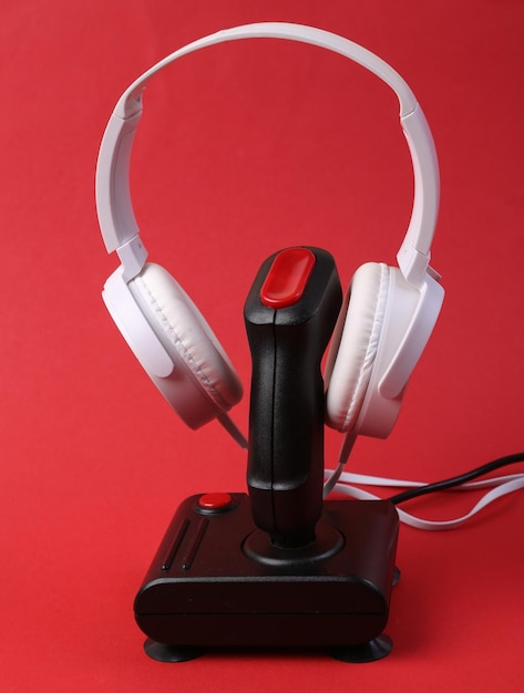 Auriculares estéreo blancos con joystick retro sobre fondo rojo Concepto de juego