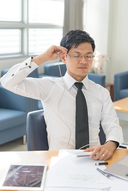 Auriculares guapos de hombre de negocios enchufados en su cabeza