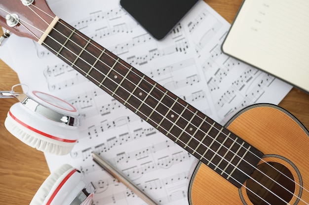 Auriculares de guitarra de madera y notas musicales en lecciones de mesa sobre el concepto de instrumento musical