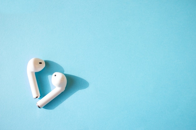 Auriculares inalámbricos blancos en una pared azul