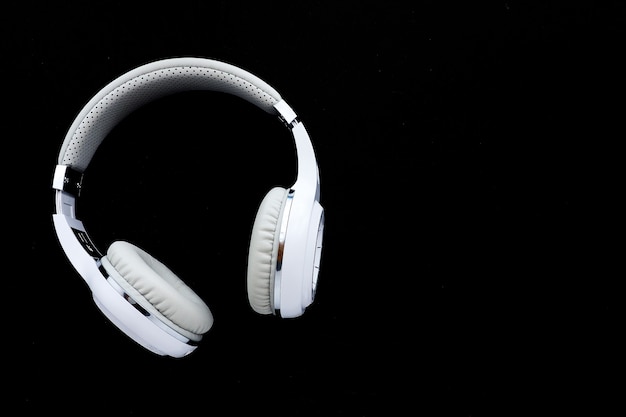 Auriculares inalámbricos blancos sobre fondo negro. copie el espacio.