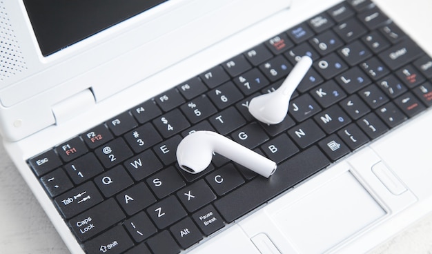 Auriculares inalámbricos blancos en el teclado del portátil.