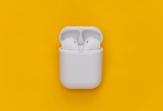 Auriculares inalámbricos modernos con estuche de carga sobre fondo amarillo.