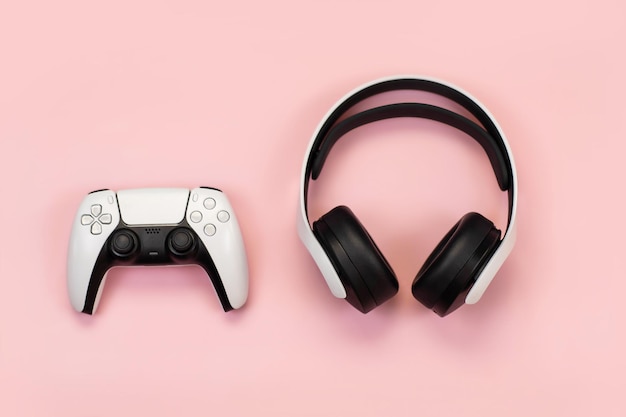 Auriculares y joystick para jugar en una consola de computadora con diseños de fondo rosa