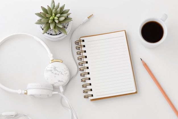 Auriculares con libreta en escritorio blanco