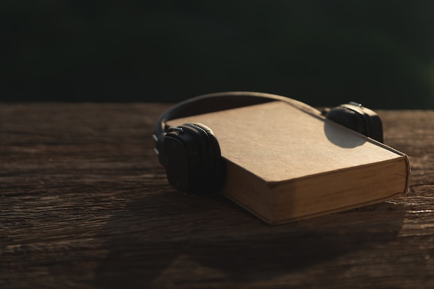 Auriculares y libro antiguo en madera