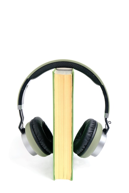 Auriculares y un libro sobre un fondo blanco. Escuche audiolibros en línea.