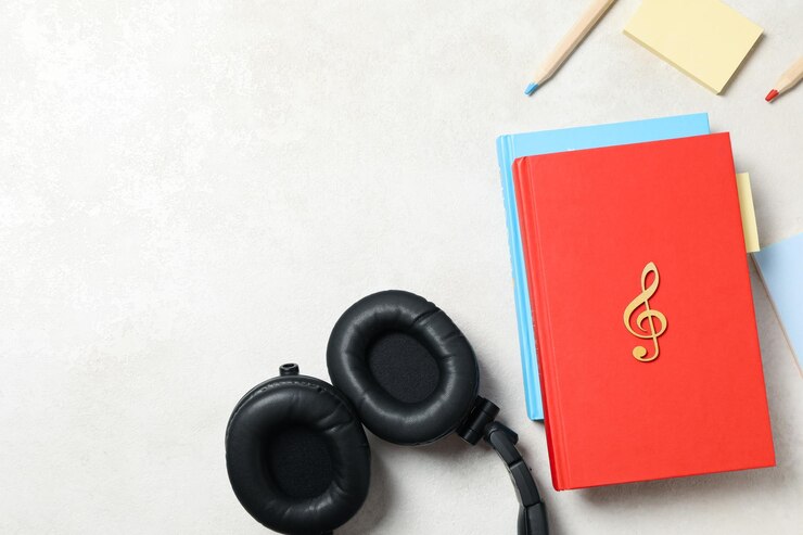 Auriculares, libros y lápices sobre fondo claro, espacio para texto.
