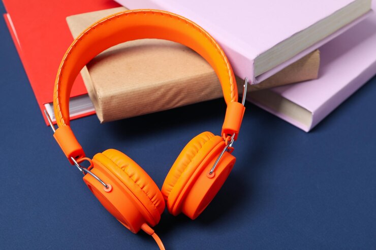 Auriculares en libros sobre fondo azul de cerca