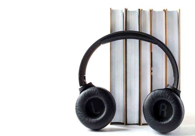 Auriculares y libros sobre un fondo blanco. Concepto de audiolibro con espacio de copia.