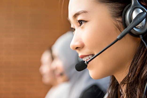 Auriculares del micrófono de la mujer que llevan asiática hermosa que trabajan en centro de atención telefónica