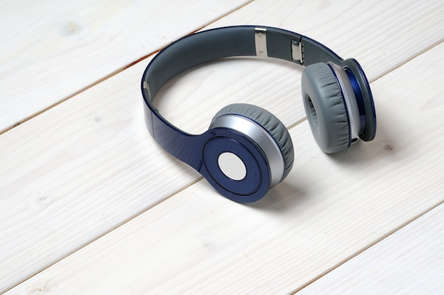 Auriculares modernos azules y plateados para escuchar música en una madera blanca