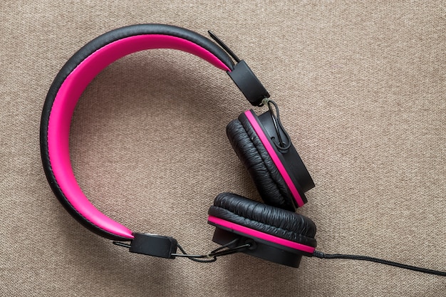 Auriculares negro y rosa aislado sobre tela ligera plana