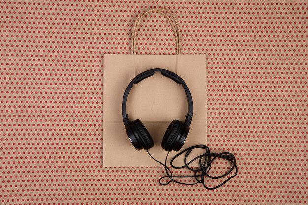 Foto auriculares negros y bolsas de regalo de bolsas de compras a rayas hechas a mano sobre fondo de papel artesanal