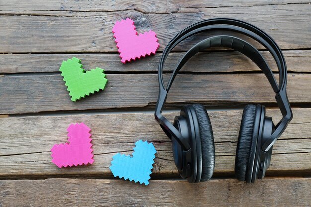 Auriculares negros con corazones sobre fondo de madera