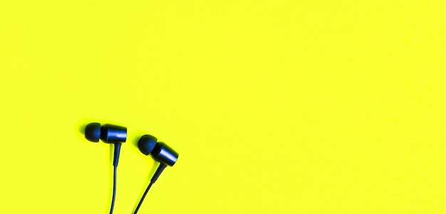 Auriculares negros sobre fondo amarillo. Concepto de música moderna. Tecnología de audio.
