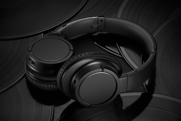 Auriculares negros sobre un fondo negro mate de discos de vinilo vista superior Auriculares Bluetooth