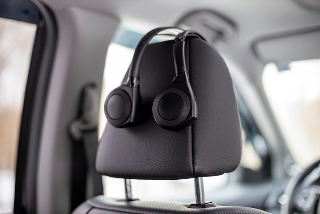 Los auriculares en el oído cuelgan del reposacabezas en la tecnología de automóviles sistema multimedia personal