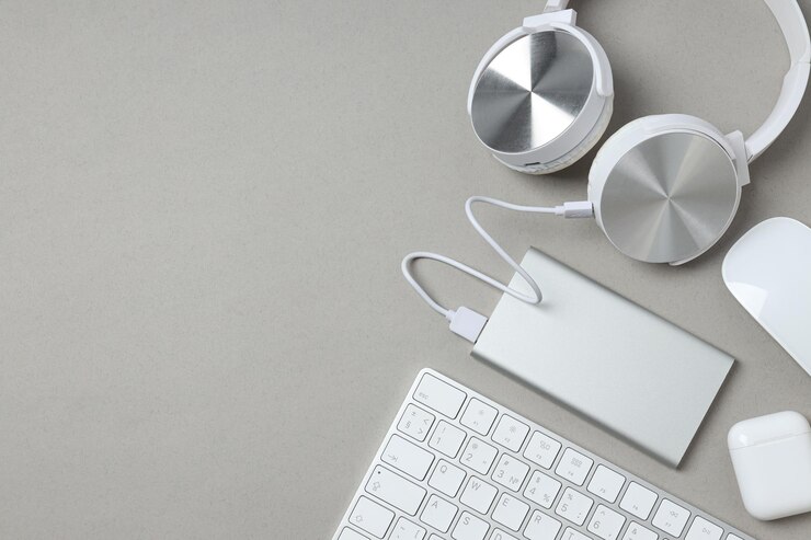 Auriculares Powerbank y teclado en espacio de fondo gris para texto