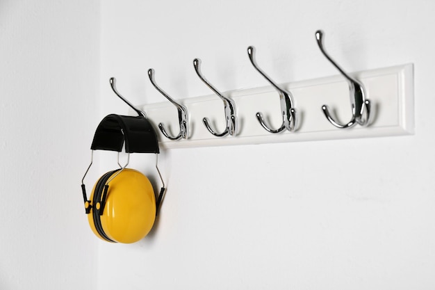 Auriculares protectores colgados en la pared blanca Equipo de seguridad