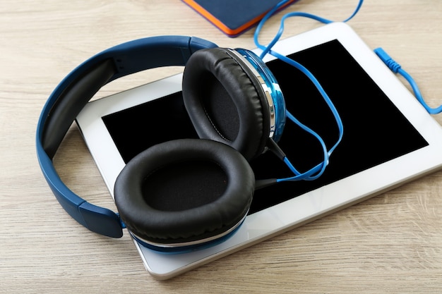 Auriculares con tableta en la mesa de madera de cerca