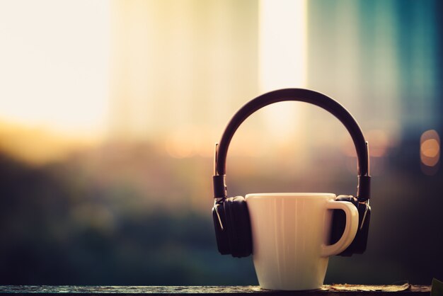 Auriculares y taza de café en la ciudad borrosa