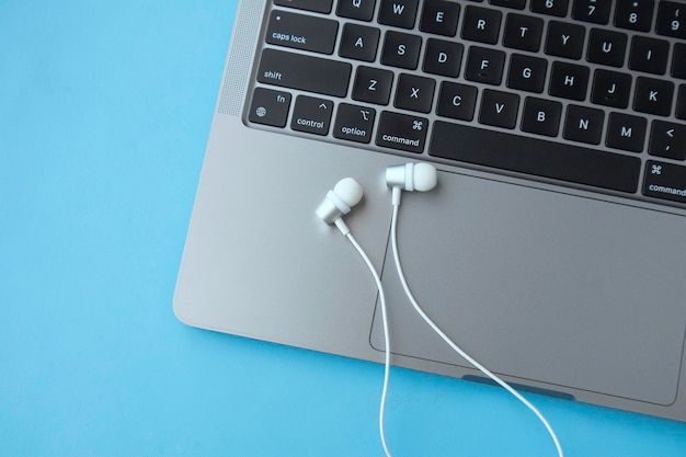 Auriculares y teclado portátil sobre fondo azul.