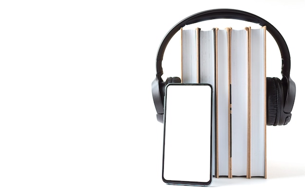 Auriculares, teléfono y libros sobre un fondo blanco. Concepto de audiolibro.