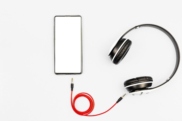 Foto auriculares y un teléfono sobre un fondo blanco listo para escuchar música