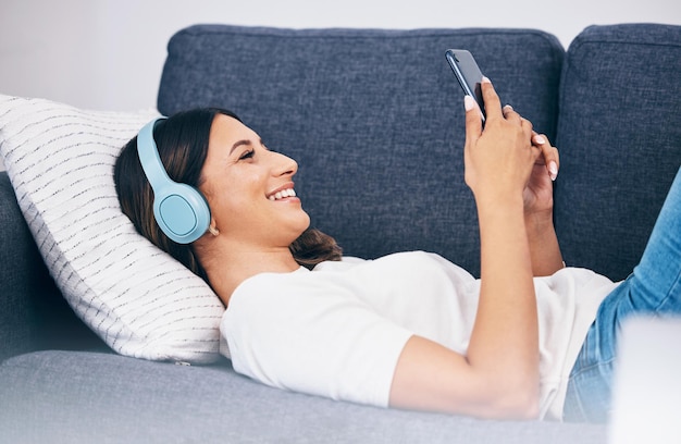 Auriculares teléfono y sofá mujer o estudiante con meme video chat en internet y música para la salud mental y relajarse Smartphone de persona en el sofá escuchando audio o un podcast divertido en línea