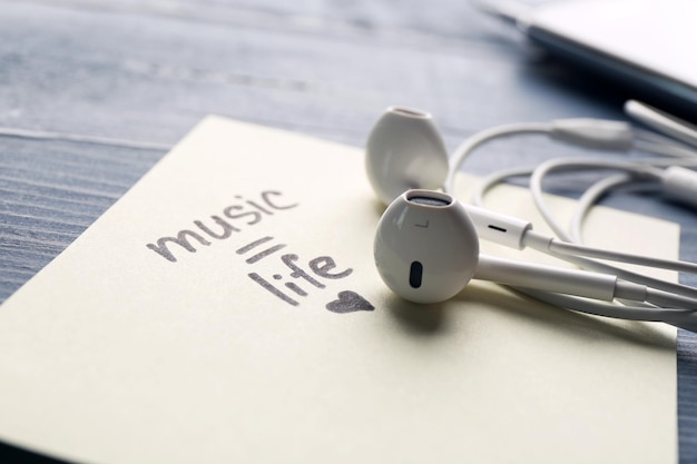 Foto auriculares con texto vida musical en pegatina en primer plano de la mesa de madera