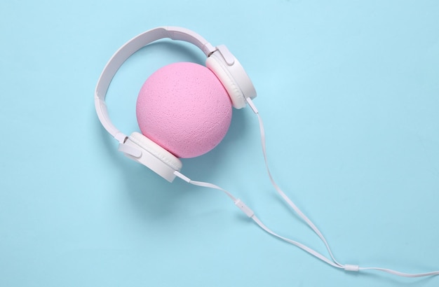 Auriculares usados en bola rosa sobre fondo azul Diseño creativo Concepto de música minimalista