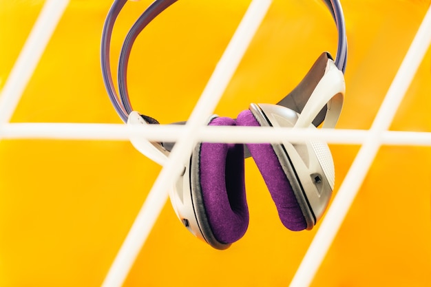 Auriculares violetas sobre naranja sostenidos por el hombre y parrilla en frente