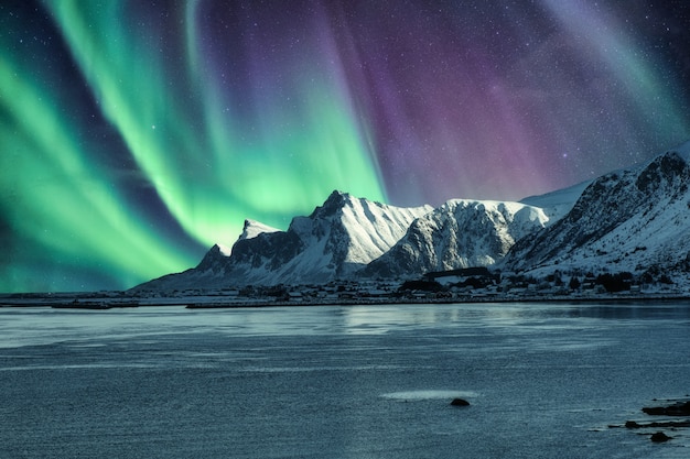 Aurora boreal, aurora boreal arriba de la montaña nevada en las islas Lofoten