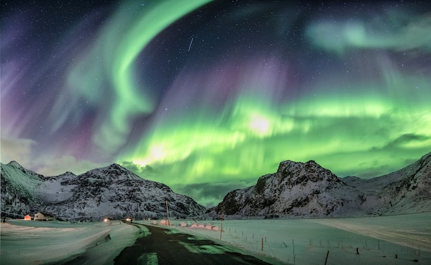 Aurora boreal, aurora boreal sobre a cordilheira de neve em flakstad, ilhas lofoten, noruega