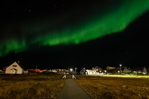Aurora boreal e céu estrelado sobre o assentamento com casas vivas e estrada Nuuk Greenland